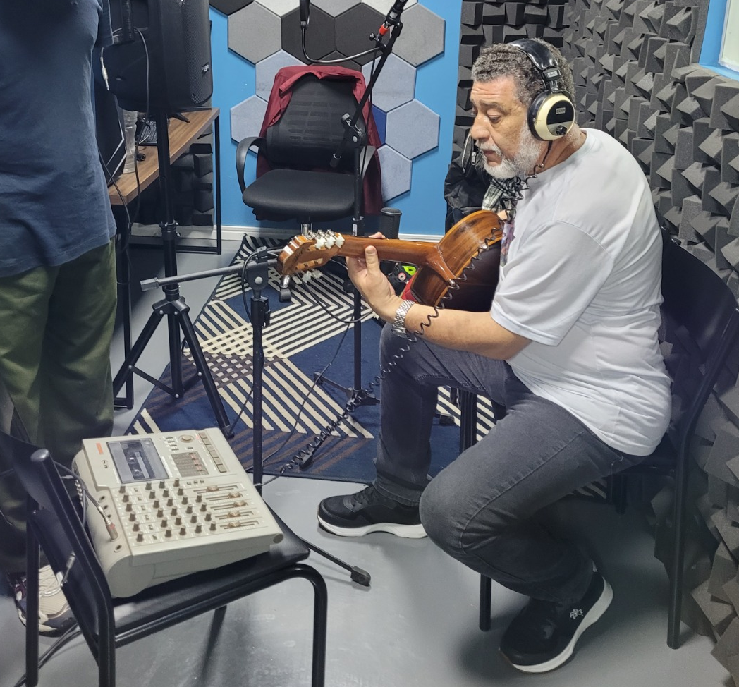 Clóvis Ribeiro dedilhando violão durante ensaio no estúdio