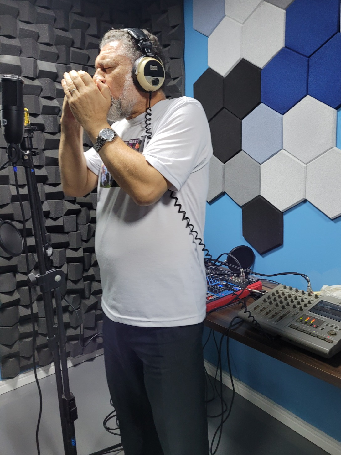 Clóvis Ribeiro cantando próximo ao microfone de estúdio